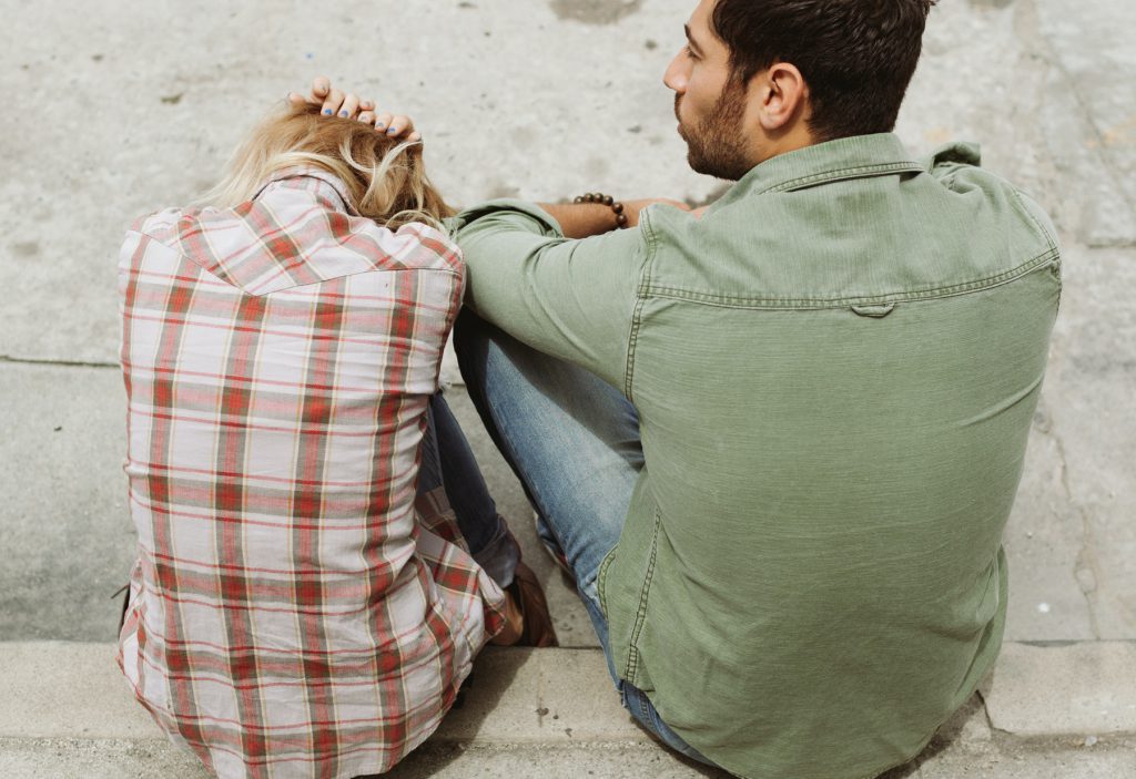Man and woman sitting on the curb, arguing over a relationship problem. You can get help in couples therapy in Wesley Chapel, FL  and in Marriage counseling in Wesley Chapel, FL  and in online counseling in florida with christian therapists at Sheltering Oaks Counseling
